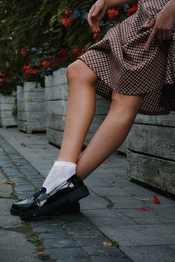 Shot of person leaning against wall (legs in loafers shown)