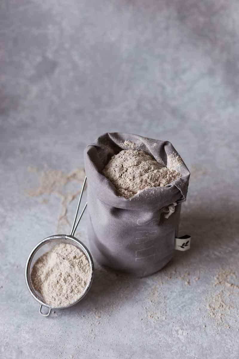 Bag of flour with measuring cup of flour next to it