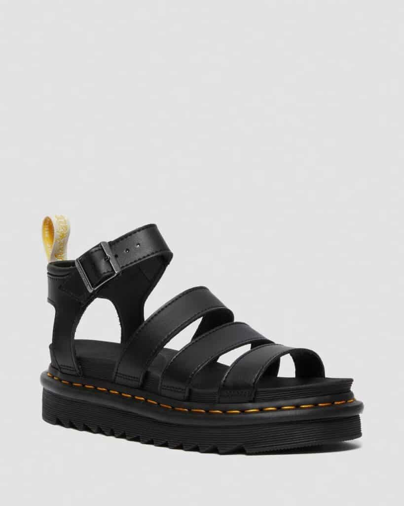 Vegan Dr Martens black vegan leather Blaire fisherman sandals. They have three straps over the foot and a buckled ankle strap, the iconic Doc Marten yellow stitching, and come with black soles.