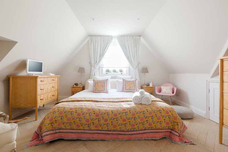 Bedroom in Kew Gardens B and B: attic room with chair and TV on chest of drawers