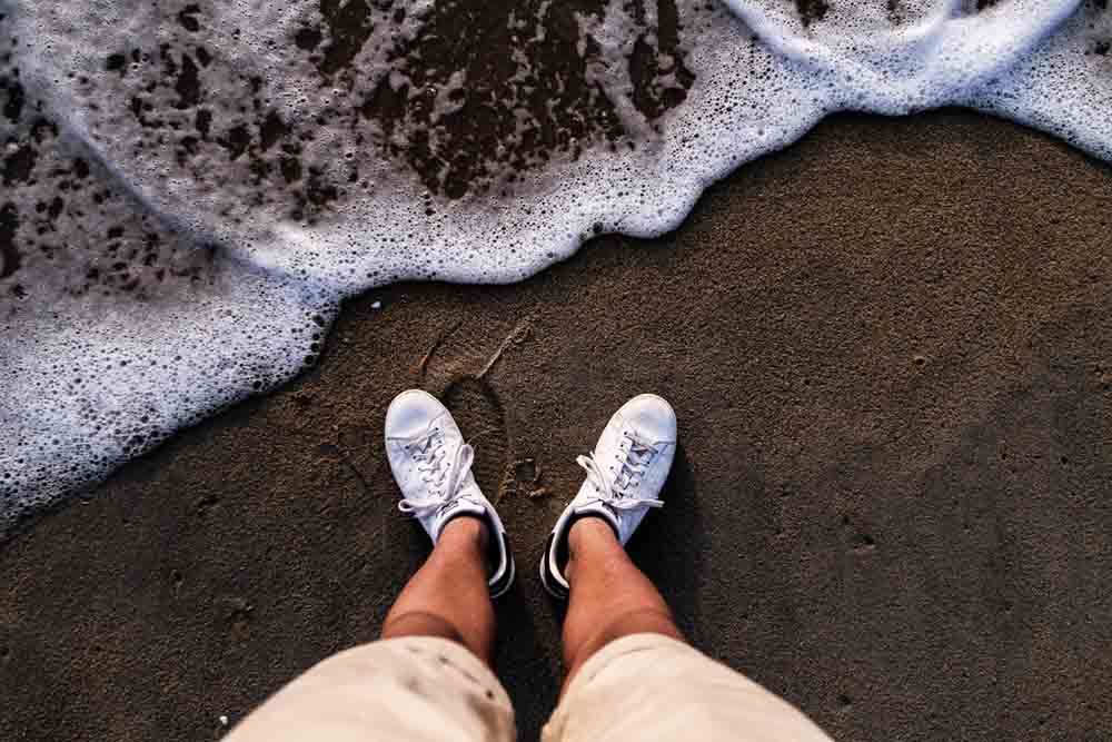 White Stan Smith Adidas sneakers on the beach