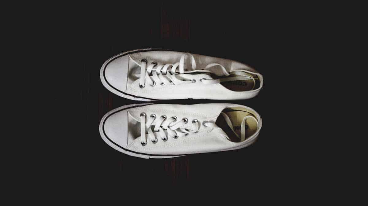 Overheard shot of white canvas sneakers on black background