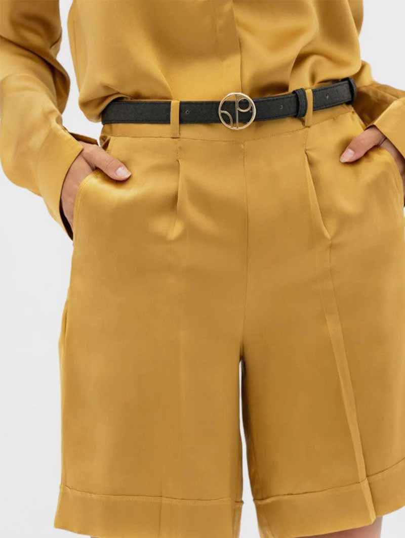 Black vegan pineapple leather skinny belt shown on model wearing yellow playsuit