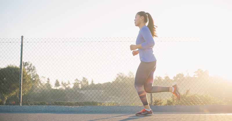 Woman in ponytail and multicoloured leggings runs