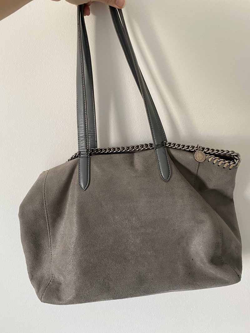 Author holding Stella McCartney tote bag (grey vegan leather with signature chain trim)